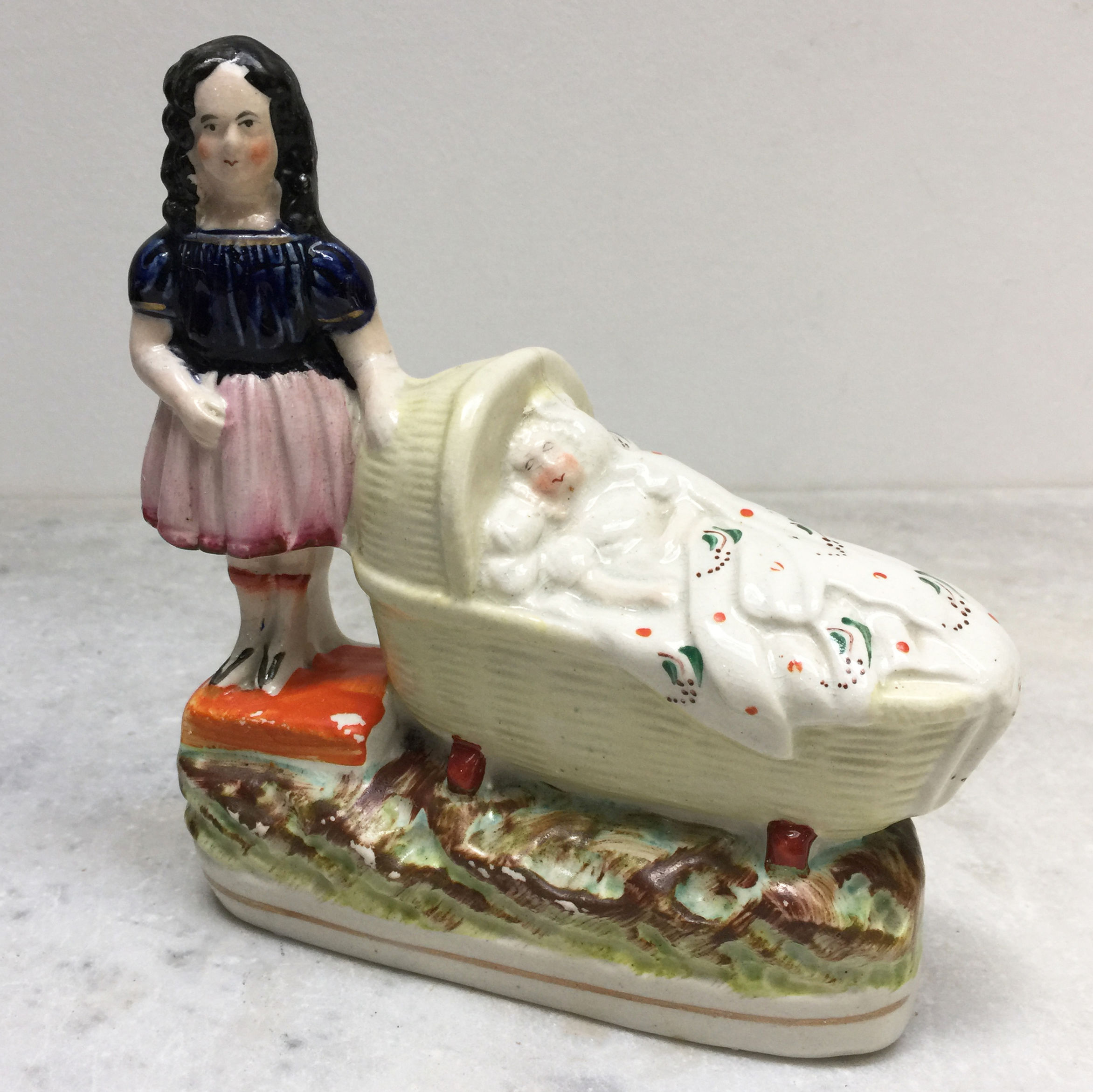 Staffordshire Figure Of A Girl & A Baby In A Crib