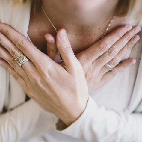 Woman with hand on heart, eyes closed, attending to her body's quiet signals; body awareness and nervous system healing
