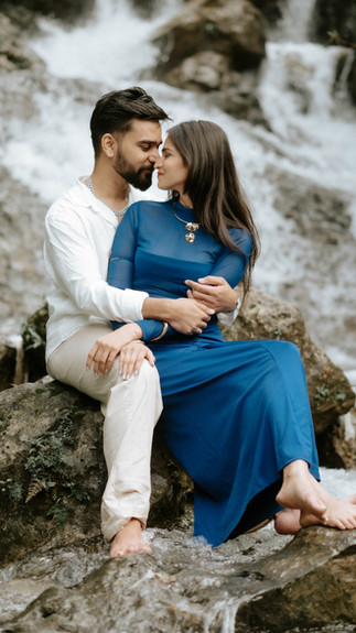 Couple sitting by a waterfall in Dehradun during a nature-inspired pre-wedding session.