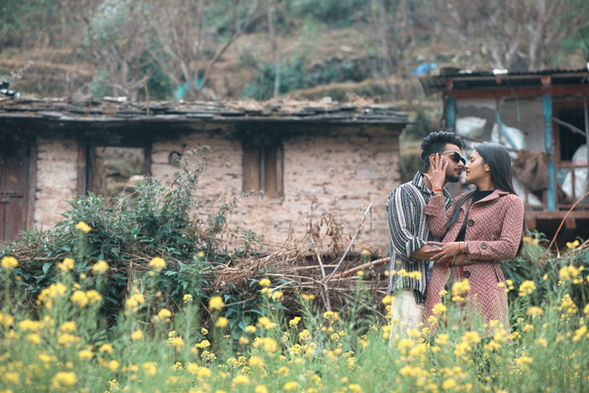 Couple kissing gently in front of a rustic building amid nature