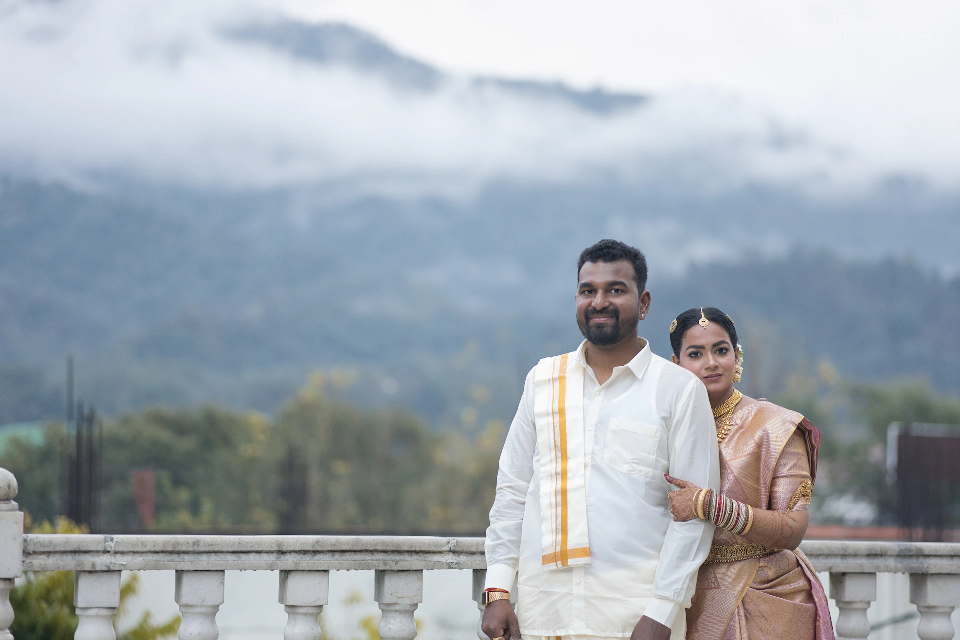 Traditional pre wedding couple portrait in Rishikesh with scenic mountain backdrop, bride in silk saree and groom in white outfit posing naturally, Uttarakhand wedding photography