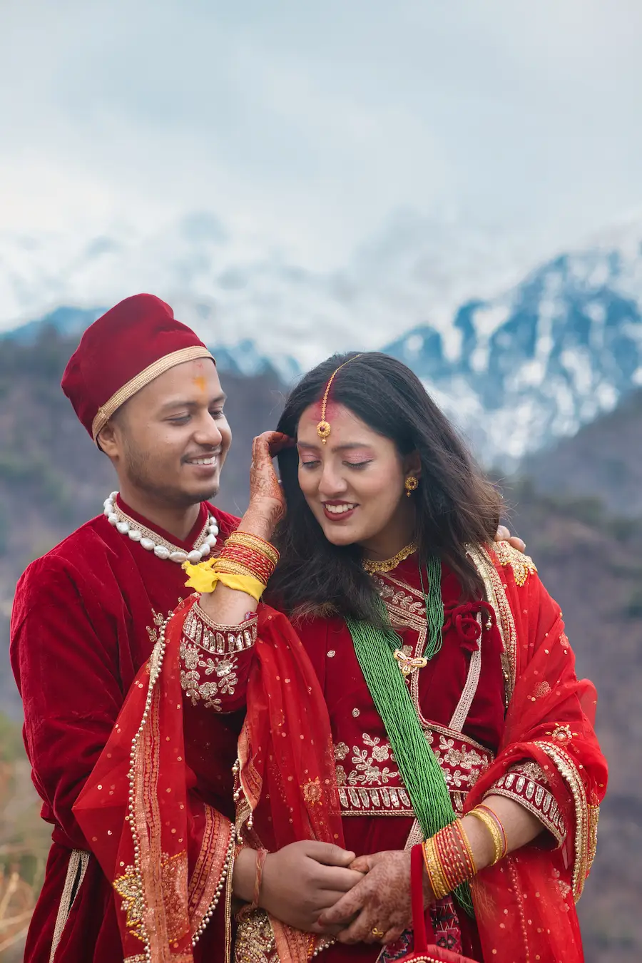 Indian wedding couple smiling together in traditional outfits with mountain backdrop
