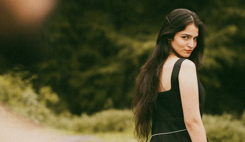 Bride in black gown walking through lush greenery during her pre wedding photoshoot in Mussoorie.