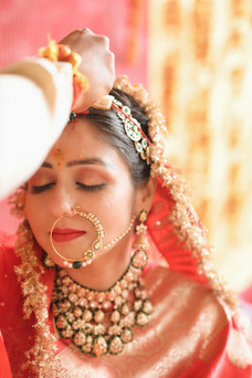 Groom applying sindoor in bride’s hair parting during Hindu wedding ceremony.