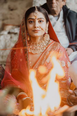 Close-up of Indian bride in red saree sitting near sacred fire at Triyuginarayan Temple