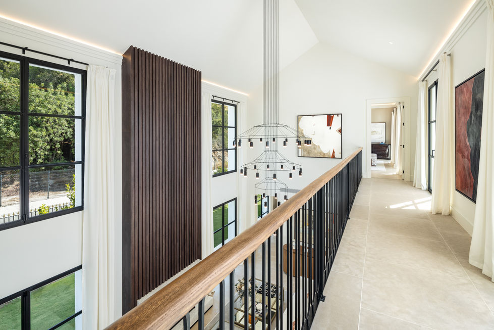a staircase with a wooden railing and a chandelier hanging from the ceiling