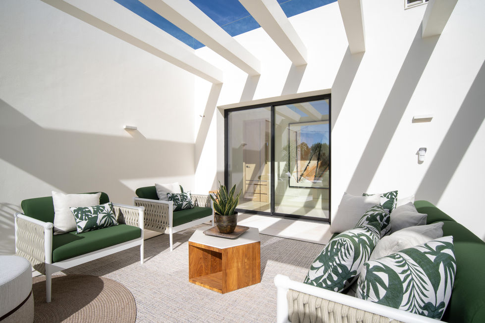 a patio with green and white furniture and a wooden table
