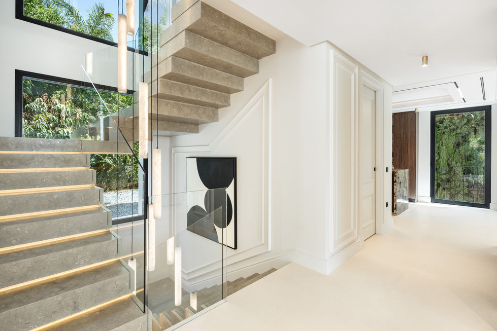 a staircase with a glass railing and a painting on the wall
