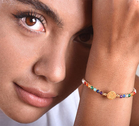 Close-up of woman wearing colorful beaded bracelet with gold charm.