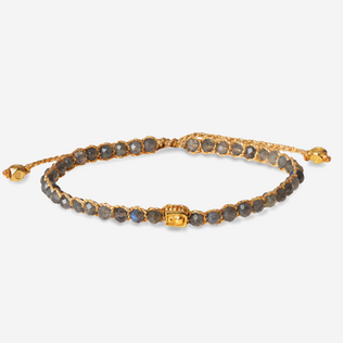Handcrafted dark gemstone bracelet on gold cord with a central gold bead.