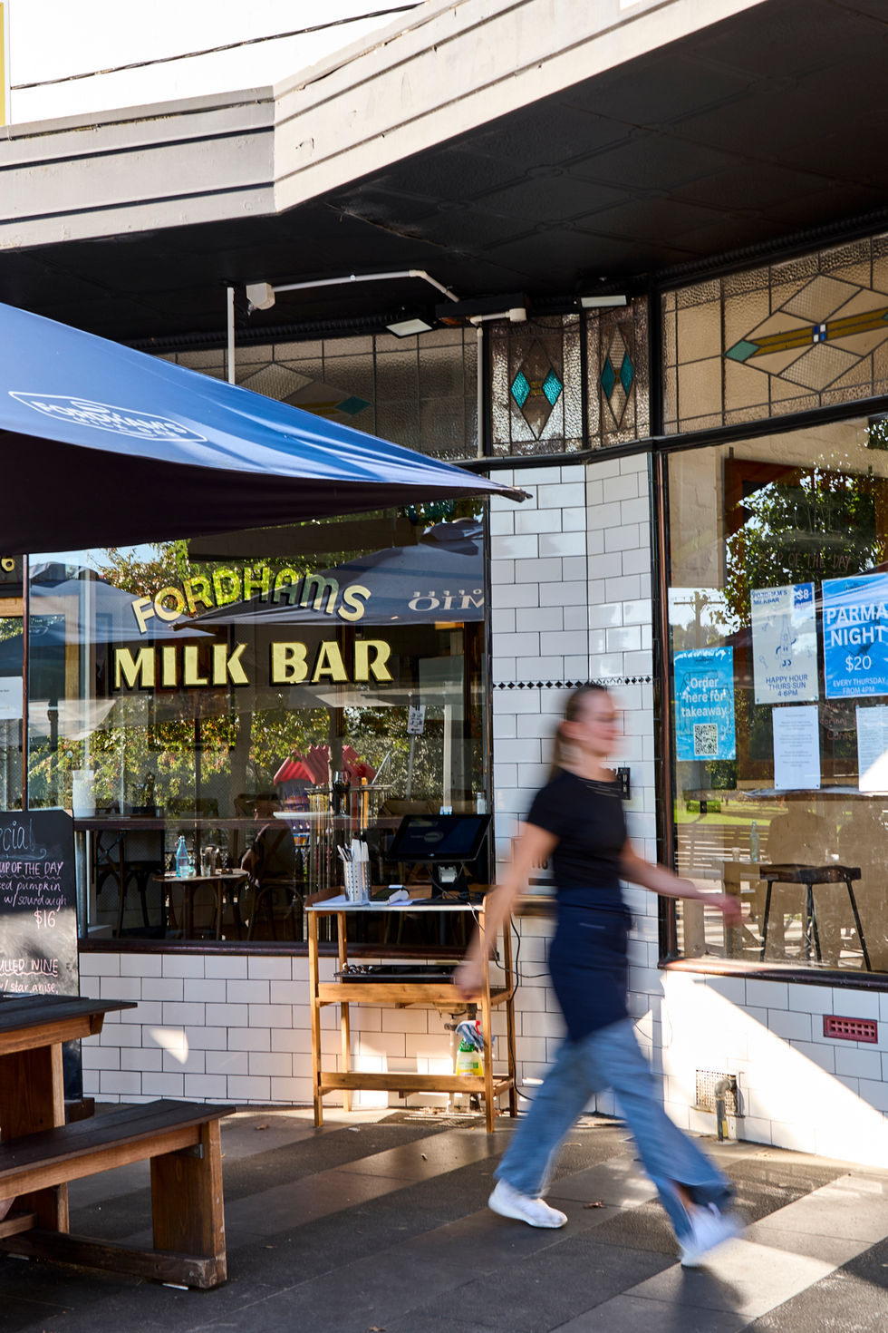 A lively cafe with patrons, hanging plants, and string lights creating a cozy atmosphere.