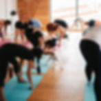 people doing yoga while a woman in a black workout outfit pets a yellow lab puppy.