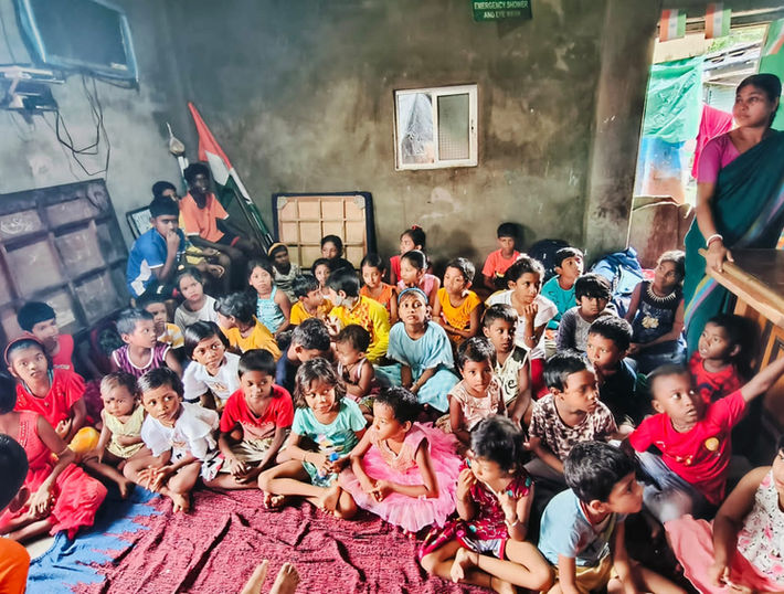 Group of children posing together indoors, with an Indian flag; NGO Punorutthan.