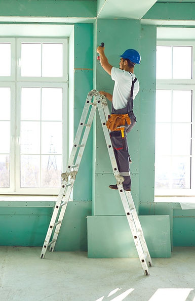 A worker on a ladder painting a wall