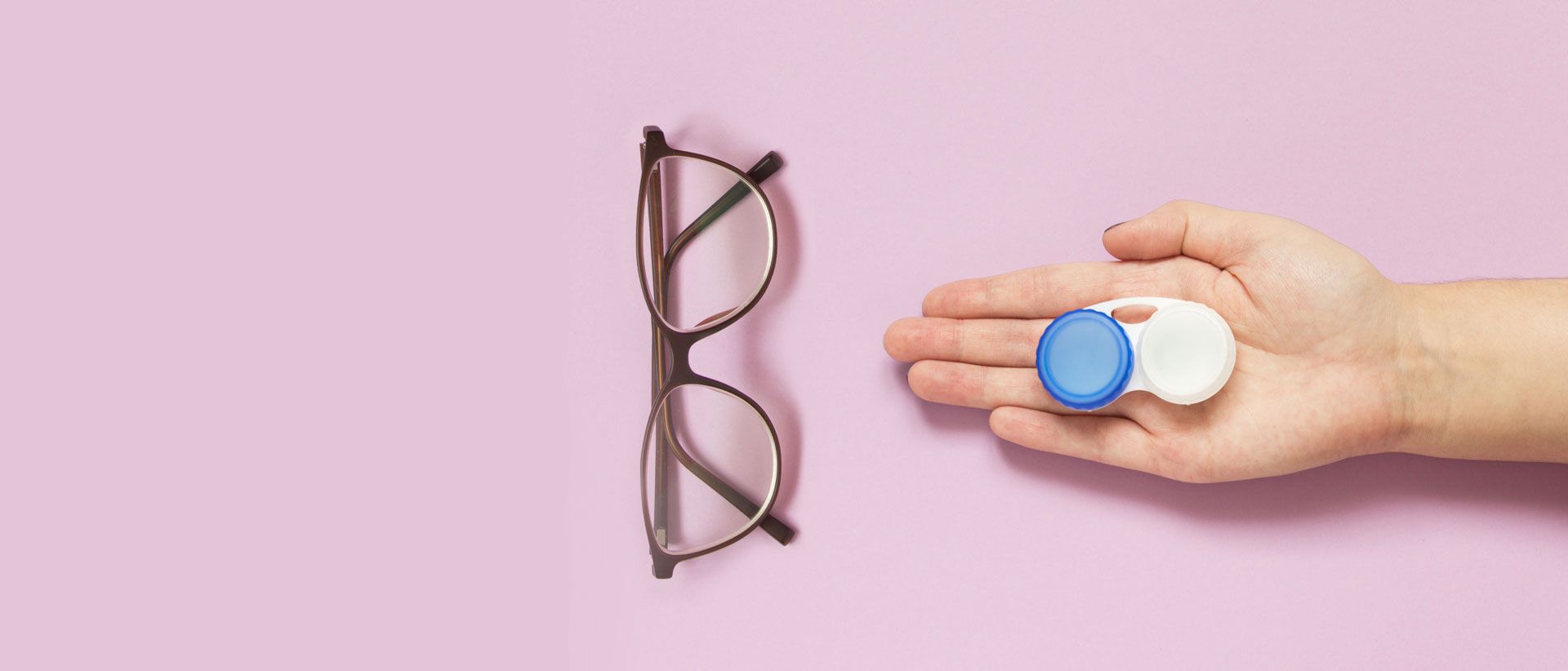 Glasses and contact lense container on pink background