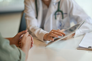 Close up of a doctor holding a tablet and talking to a patient.