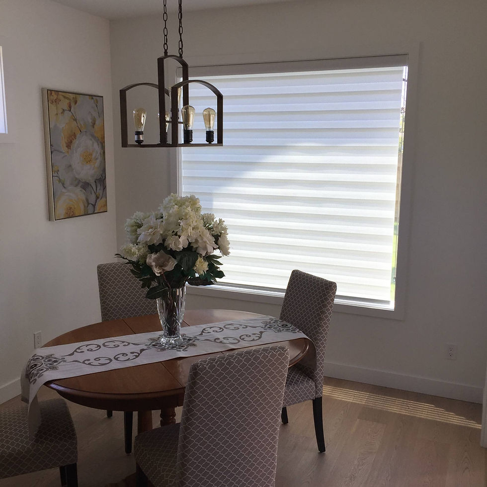 A small wooden dining table with chairs placed beside a window covered with a curtain.