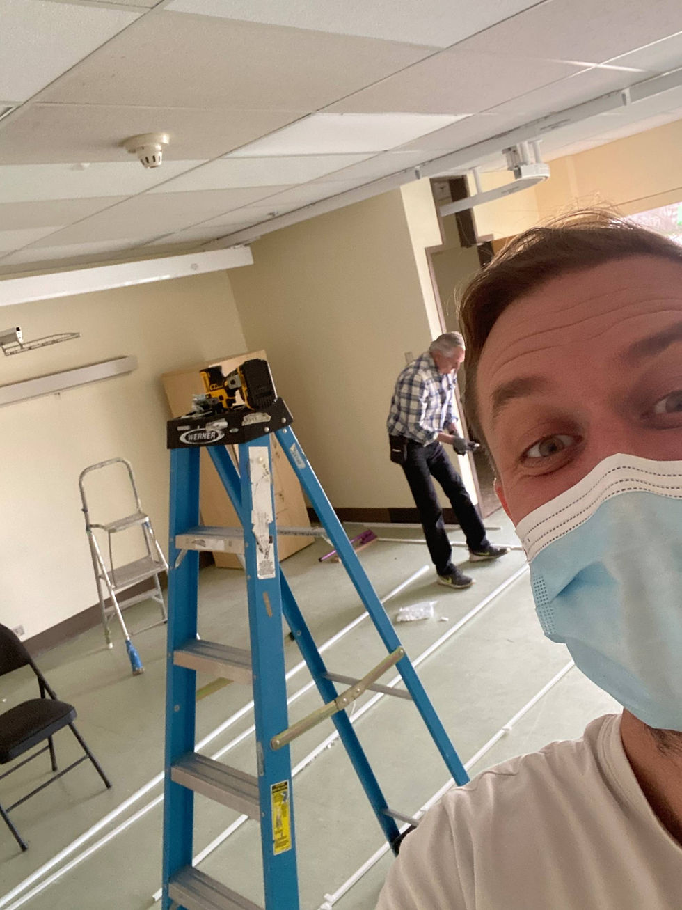 A man with a facemask taking a selfie of work in progress.