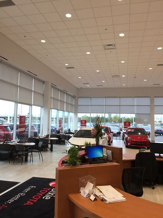 A car showroom with several windows partially covered by blackout roller blinds