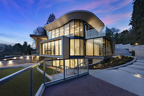 Contemporary glass house with curved roof and outdoor steps at dusk