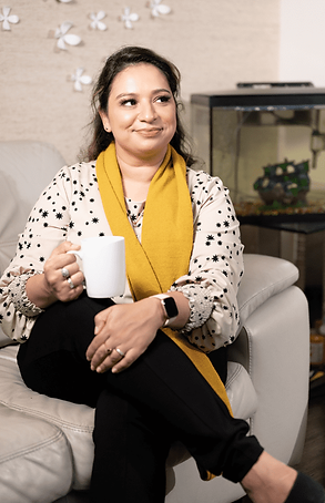 A woman sitting on a couch, holding a coffee cup