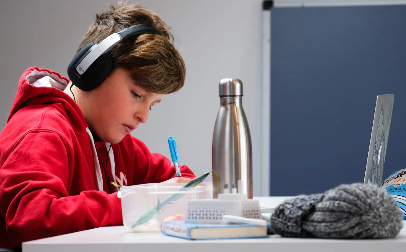 child with headphones doing homework