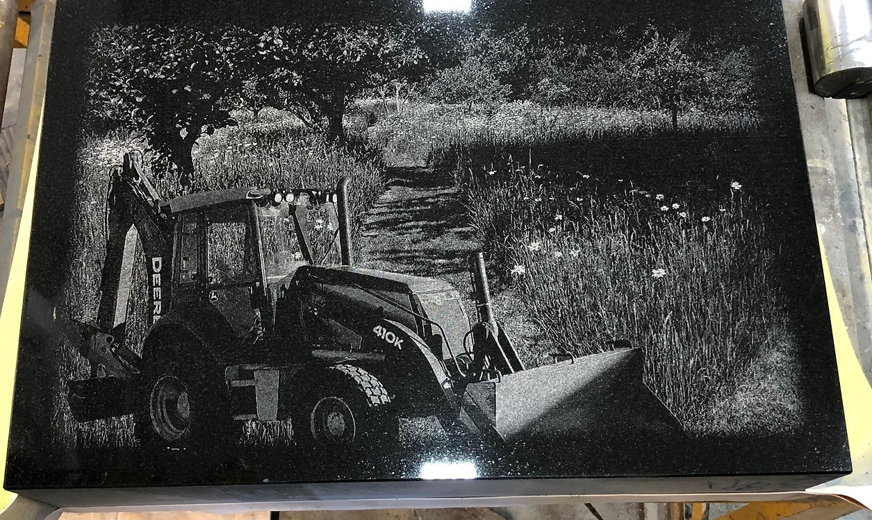 Etched tractor and field scene on granite