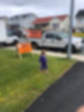 A picture of a little girl passing by two pickup vehicles