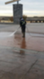 Worker washing a brick pathway