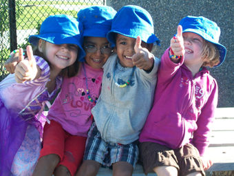Four young kids in hats sitting outside