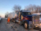 Camion transportant des équipements avec un ouvrier sur le côté