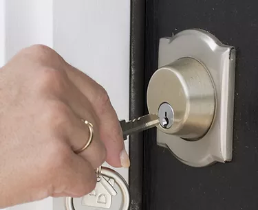 man opening the door lock with a key