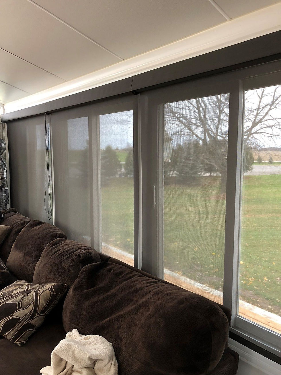 Side angle view of a series of living room windows covered by inside-mounted window shades