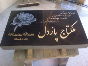 Black granite headstone with rose, text in Farsi, and Mulktaj Pazdel March 18, 2019.
