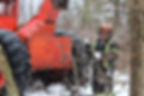 Un abatteur d'arbres à côté d'une nacelle au milieu d'une forêt d'hiver.