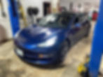 A picture of a man inside a blue-coloured car parked inside a car repair facility