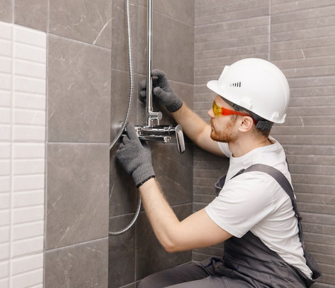 plumber installing new faucet and shower system after bathroom renovation