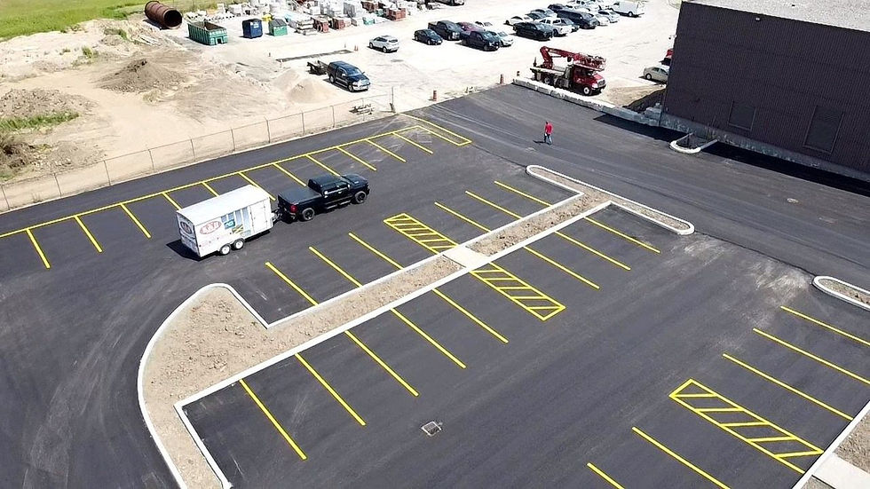 A large section of a parking lot that has been marked right next to an unfinished parking lot