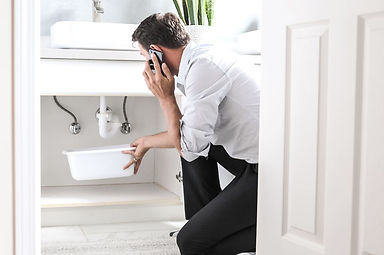 man collecting water leaking under the sink