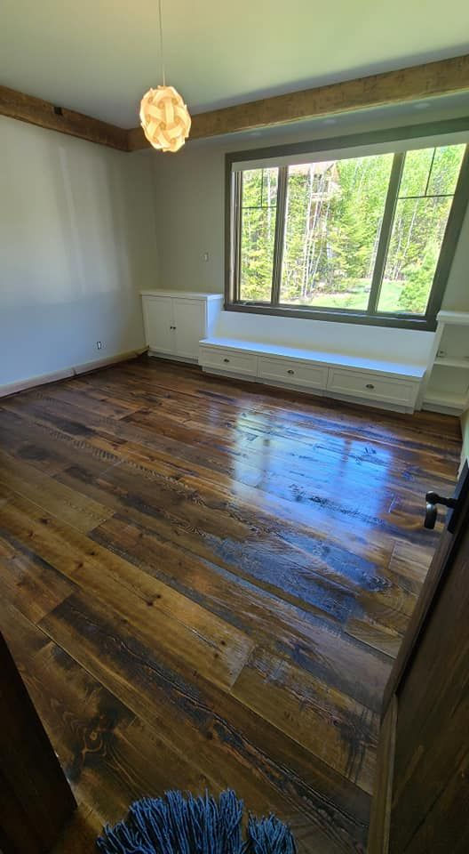 Une pièce vide avec un plancher en bois et une vue sur l'extérieur.