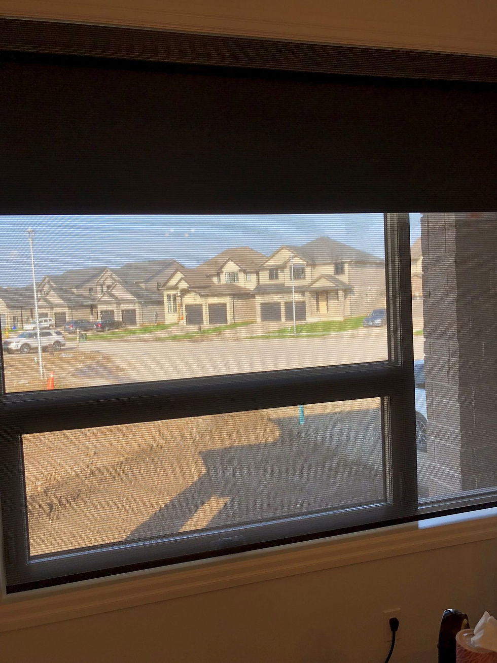 A small window partially covered by a black window blind