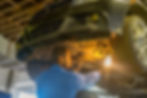 mechanic with light under car