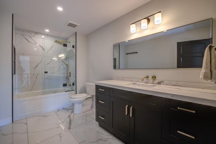 A picture of beautiful bathroom with a bath tub, cabinets, sink and a big rectangular mirror