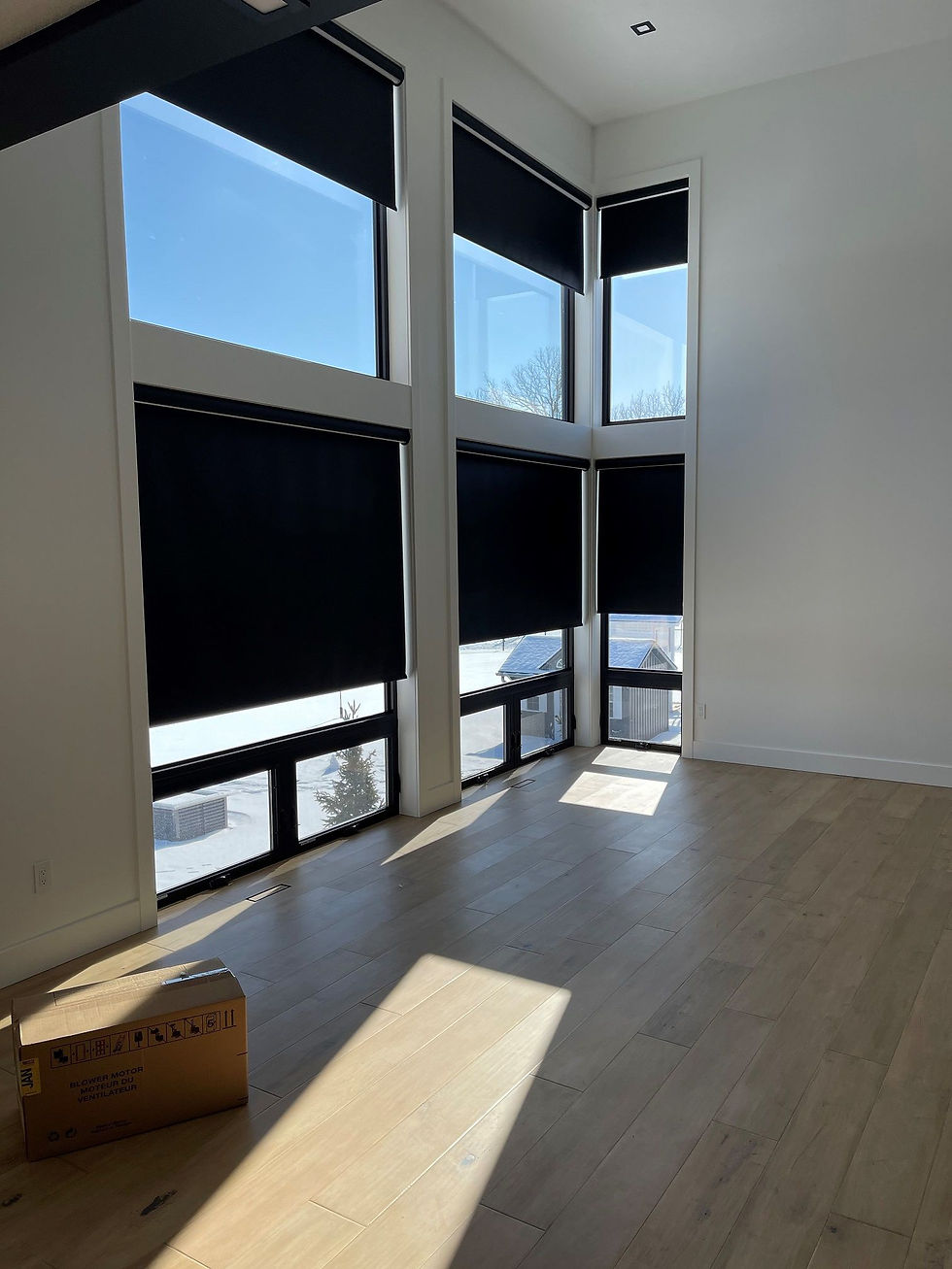 A large window unit partially covered by blackout blinds