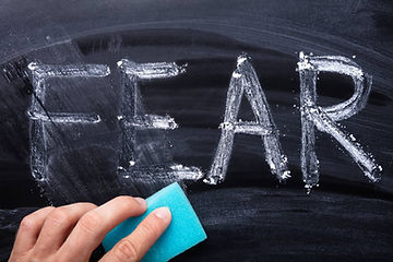 someone removing fear written on a blackboard
