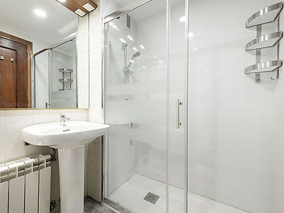 Toilet with glass shower stall, white porcelain sink in an apartment