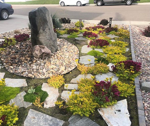 View of flowering plants in the driveway of a large house