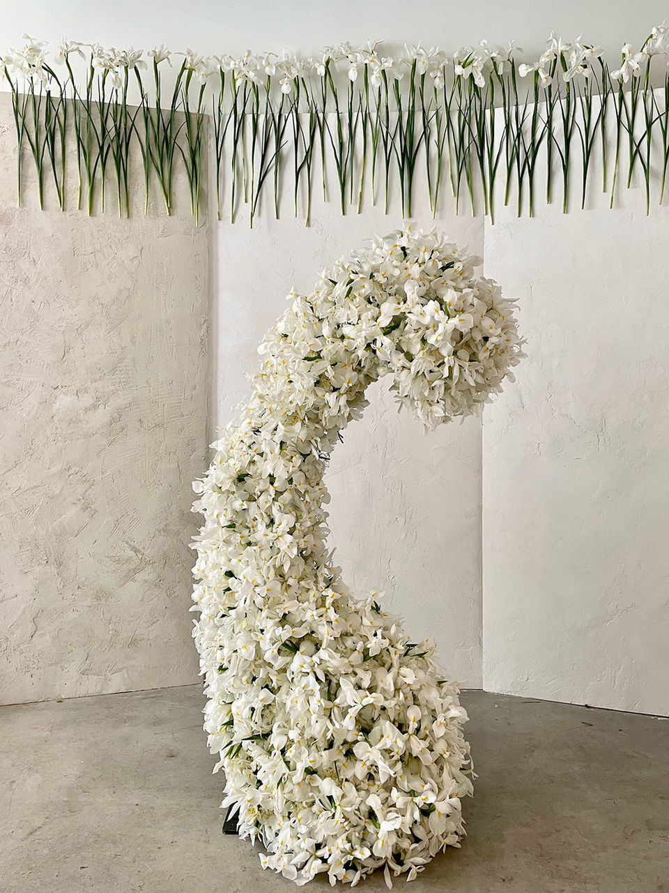 white iris installation in form of a bean with hanging iris in background.