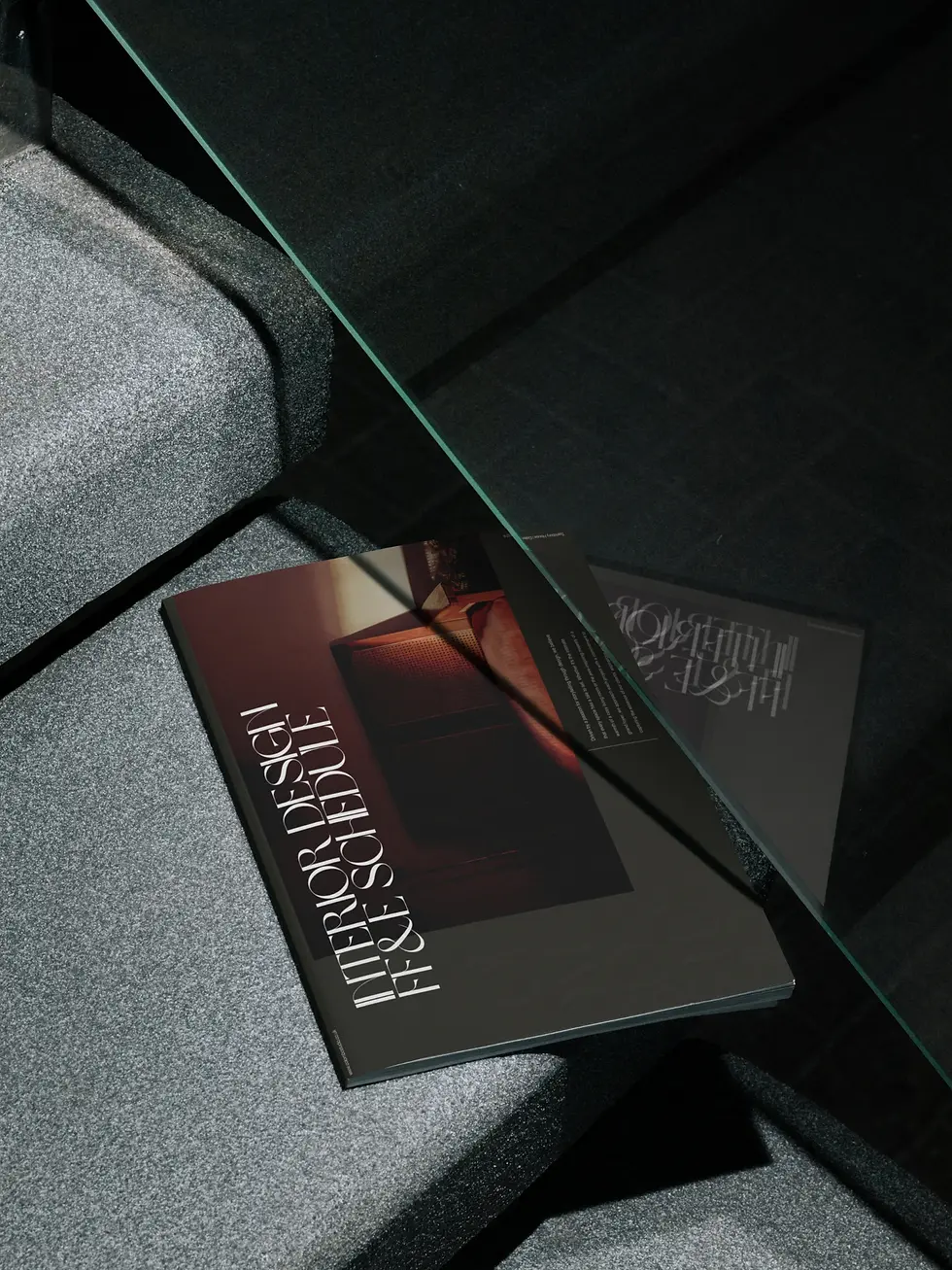 Magazine titled "Interior Design FF&E Schedule" on a gray upholstered surface under glass, creating a modern and sophisticated ambiance.