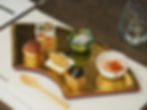 金色の器に和食の前菜が美しく盛られた懐石料理の一皿。木製スプーンとグラスが添えられ、上品で静かな雰囲気。